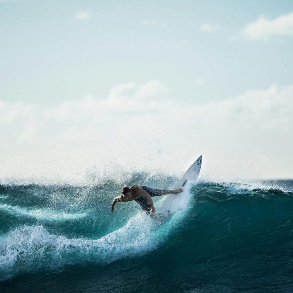 Thrilling action shot of a surfer riding the waves under a clear sky.